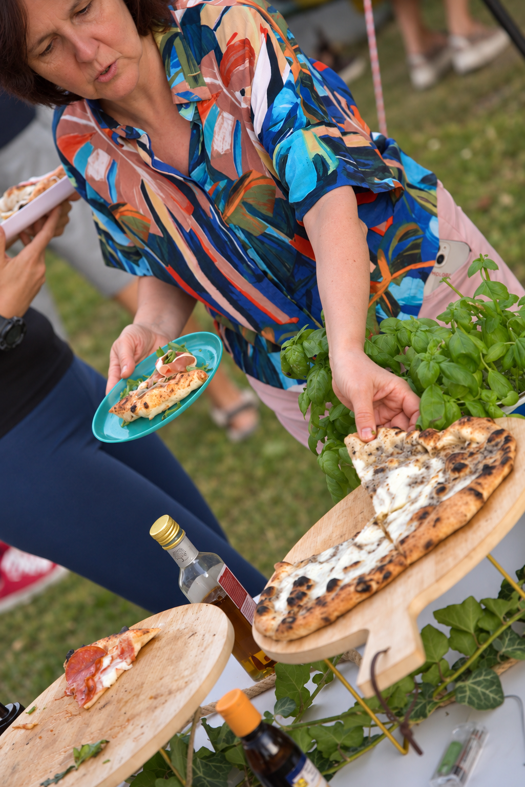 Vendég frissen sült pizzát vesz a kerti asztalnál